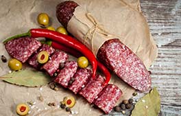 Aceitunas, salame y aji sobre madera